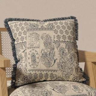 The "Chhaya Fringes" cushion cover placed on a light-toned chair, demonstrating its artistic and traditional charm in a home setting.