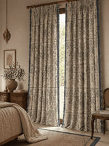 Decorative chhaya Indian curtains in a room with a bed and side table.