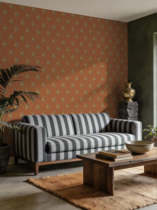 A luxury modern sofa upholstered in Chitra charcoal and grey striped fabric set against a terracotta floral wallpaper and rustic wood table.