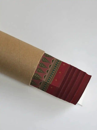 Chitrakar wall art print in madder red rolled in a kraft shipping tube, showing the olive cypress border detail.