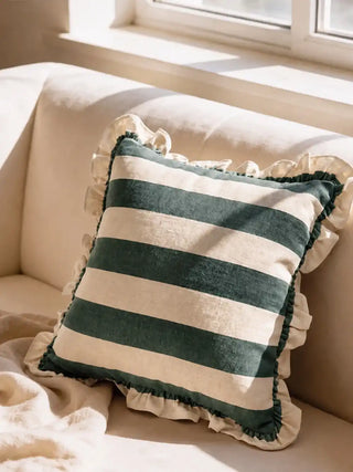 Cinnamon ruffle cushion cover in green resting on a cream sofa in soft window light in a living room.