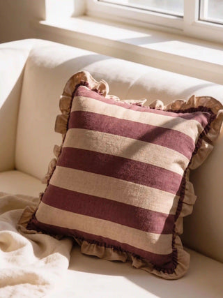 The Cinnamon Stripe Ruffle linen cushion cover styled as a classic accent on a plush cream contemporary sofa.