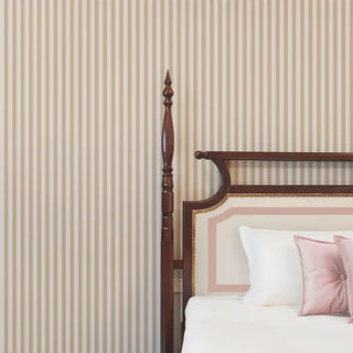 Classic Harmony Beige & Cream Stripe Wallpaper behind a wooden bedframe with white and blush bedding, adding a warm and timeless touch.