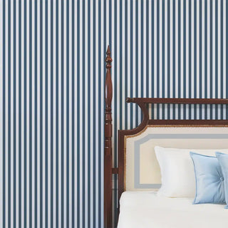 Blue and white striped wallpaper applied behind a wooden bed with crisp white and light blue bedding, creating a fresh and classic look.