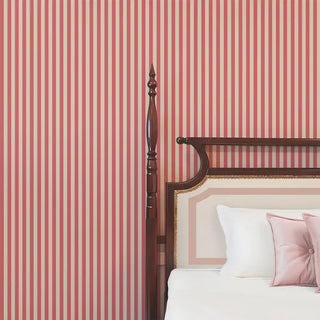 Red and cream striped wallpaper behind a wooden bed with soft neutral bedding, creating a warm and elegant look.