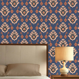 A blue wallpaper featuring a traditional nomadic-inspired motif in warm beige and terracotta tones, styled behind a bed with a lamp.