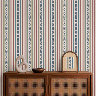 A striped wallpaper in red, blue, and cream tones applied behind a wooden console with rattan doors and decorative accents.