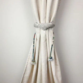 Cloudloom Handcrafted Curtain Holdback secured around a textured cream curtain, highlighting the wave pattern and colorful cords.