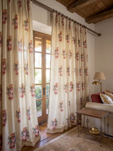 A pair of Cotswold Rose custom linen curtains beautifully framing sunlit French doors next to a rustic wooden stool.