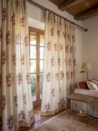 A pair of Cotswold Rose custom linen curtains beautifully framing sunlit French doors next to a rustic wooden stool.