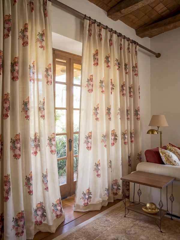 A pair of Cotswold Rose custom linen curtains beautifully framing sunlit French doors next to a rustic wooden stool.