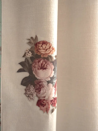 A high-resolution close-up of a printed English rose bouquet motif on the textured off-white slub linen curtain panel.