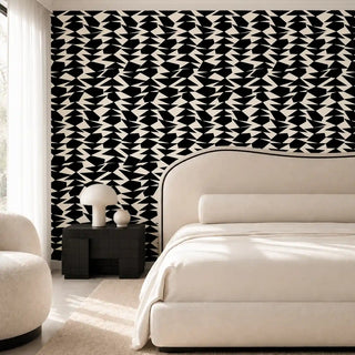 The Couture Mosaic black off white wallpaper mural installed on a feature wall in a bedroom with a cream boucle chair and black nightstand view-bedroom