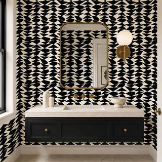 The Couture Mosaic black off white wallpaper installed above a black floating vanity with brass fixtures and a gold-framed mirror in a powder room view-powder