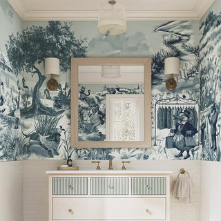 A blue countryside-inspired wallpaper featuring villagers, animals, and trees in a hand-drawn style, applied to a bathroom wall with a vanity mirror and lights.