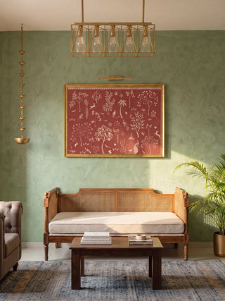 The Crimson Garden wall art framed above a cane daybed on a sage green wall with a brass hanging lamp.