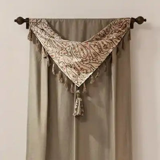 Curtain with tassels hanging on a rod against a beige wall.