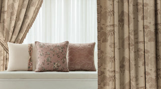 Decorative cushions on a window seat with floral patterns, surrounded by patterned ready made curtains.