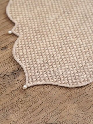 A high-resolution close-up of the mineral gray embroidered scallop border joining the linen base and jute corner panel on the Dar Alia mat.