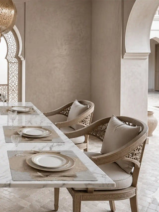 A row of Dar Alia table mats setting a sophisticated, neutral-toned tablescape across a marble dining table in a Moroccan-style arcade hall.