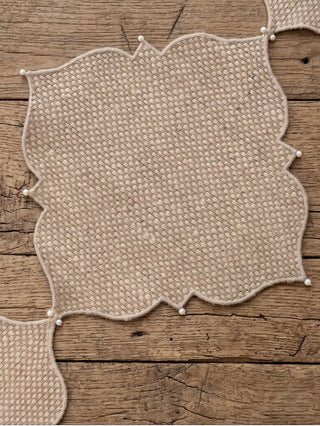 The Dar Alia rectangular linen and jute mat styled on a white marble table beneath white porcelain plates with gold rims.