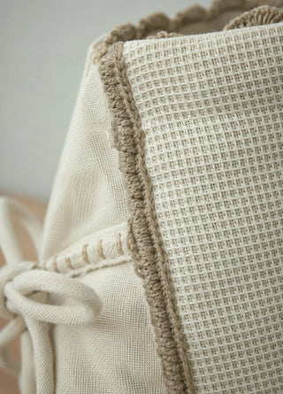 Close-up view of the Deep Lore ivory waffle cotton jug cover on a dark wood garden table