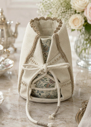 Deep Lore ivory jug cover wrapped around a floral porcelain teapot on a marble tea table with roses, macarons and gold-rimmed china.
