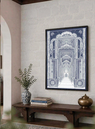 Framed Dilli Darbar wall art above a wooden bench with brass pot and stacked books in a stone-walled living room