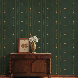 The Doriya deep emerald green pinstriped wallpaper styled in a foyer behind a dark carved wooden console table with a brass flower vase.