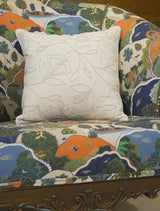 The Eden cushion cover in Ivory Vine on a patterned upholstered armchair, showing its tonal embroidered leaf and flower vine.
