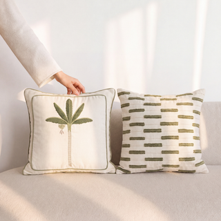 Eka Kanan palm embroidery and Ari Garden tufted dash cushions styled together on a cream boucle sofa.