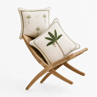 Eka Kanan and Botanical Stitch cushion covers on a rattan folding chair, sage palms embroidered on ivory