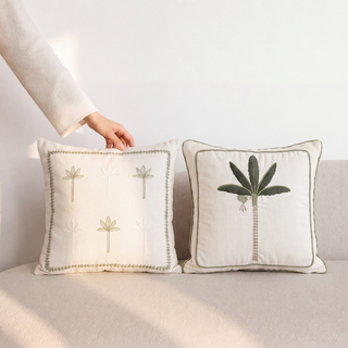 Botanical Stitch mini-palm cushion and Eka Kanan bold palm cushion styled together on a cream boucle sofa