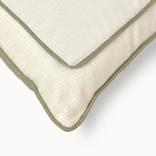 A macro close-up of the Eka Kanan cushion highlighting the linen-finish texture and the contrast sage green piping.