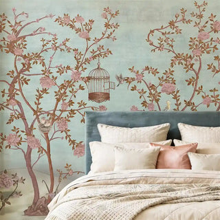 A detailed room shot of the blue garden mural behind a velvet headboard with satin rose-toned pillows.