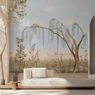 Enchanted Grove customised wallpaper with a sweeping willow tree and pale blue sky behind a mahogany dining table with floral upholstered chairs and silver candelabra