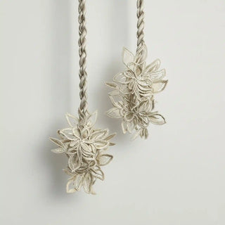 Close-up shot of the Ethereal Petals Holdback hanging, highlighting the intricate detail of the lace-like, embroidered floral motifs.