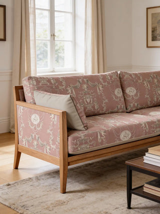 A modern wooden sofa upholstered in European Tapestry rose-pink fabric featuring classical urns and cherubs.