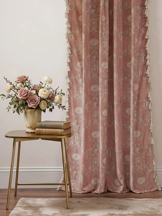 A full view of the European Tapestry curtain in dusty rose with cream tassels, styled next to a gold side table and pink roses.