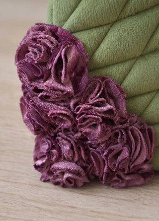 A close-up of the Finch & Flower tea cosy's mulberry fabric rosette appliqué against the moss-green quilted body.