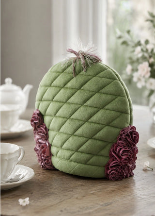 A front view of the Finch & Flower tea cosy in Moss & Mulberry showing the quilted diamond-stitch body and rosette appliqués.