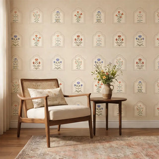 The Floral Radiance neutral botanical wallpaper styled as a feature wall in a calm lounge with a modern mid-century cane chair.