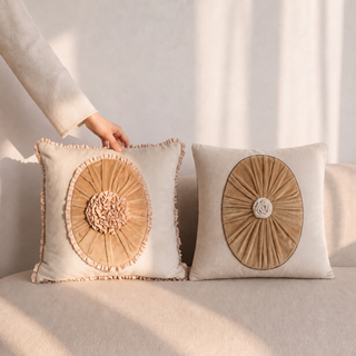 Florence Pleated ruffled velvet cushion and Frieze sunburst medallion cushion styled together on a beige sofa.