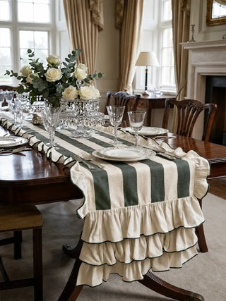 Florentine ruffle table runner in dark green laid along a mahogany dining table with china plates, cut crystal and white roses in a panelled dining room.