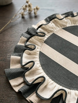 Close-up of the Florentine ruffles table mat in dark green, showing the corded edge and gathered striped ruffle on a dark wooden dining table.