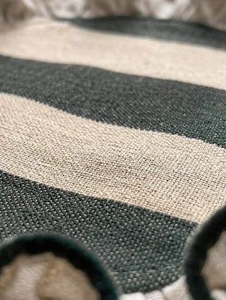 Texture close-up of the Florentine ruffles table mat in dark green, showing the handwoven linen stripes and corded ruffle edging.