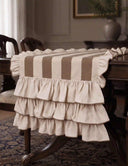 Florentine Ruffles table runner in beige and mocha draped over the end of a dark mahogany dining table showing three cascading tiers of gathered ivory ruffles with mocha overlock edge finish and herringbone stripe body