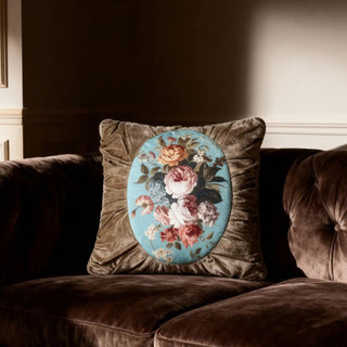 Single Florid Verona Bloom Cushion displayed on a dark brown velvet tufted sofa.