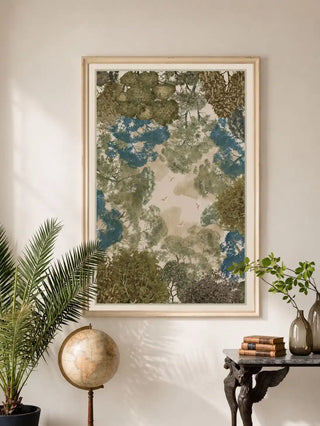The Forest Nest vintage canopy print styled inside a light wood frame over a marble-topped sideboard next to a vintage globe.