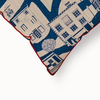 A close-up of the "French Town Pipin" cushion cover, highlighting the red piped edge and the intricate details of the illustrated town scene pattern.